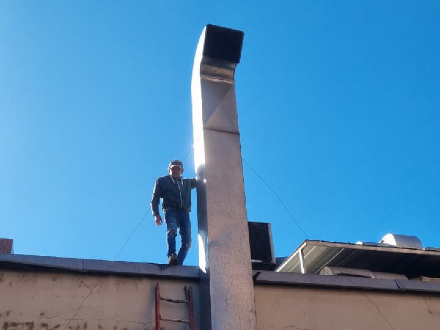 Técnico junto al ducto de extracción recién instalado, vista desde el techo